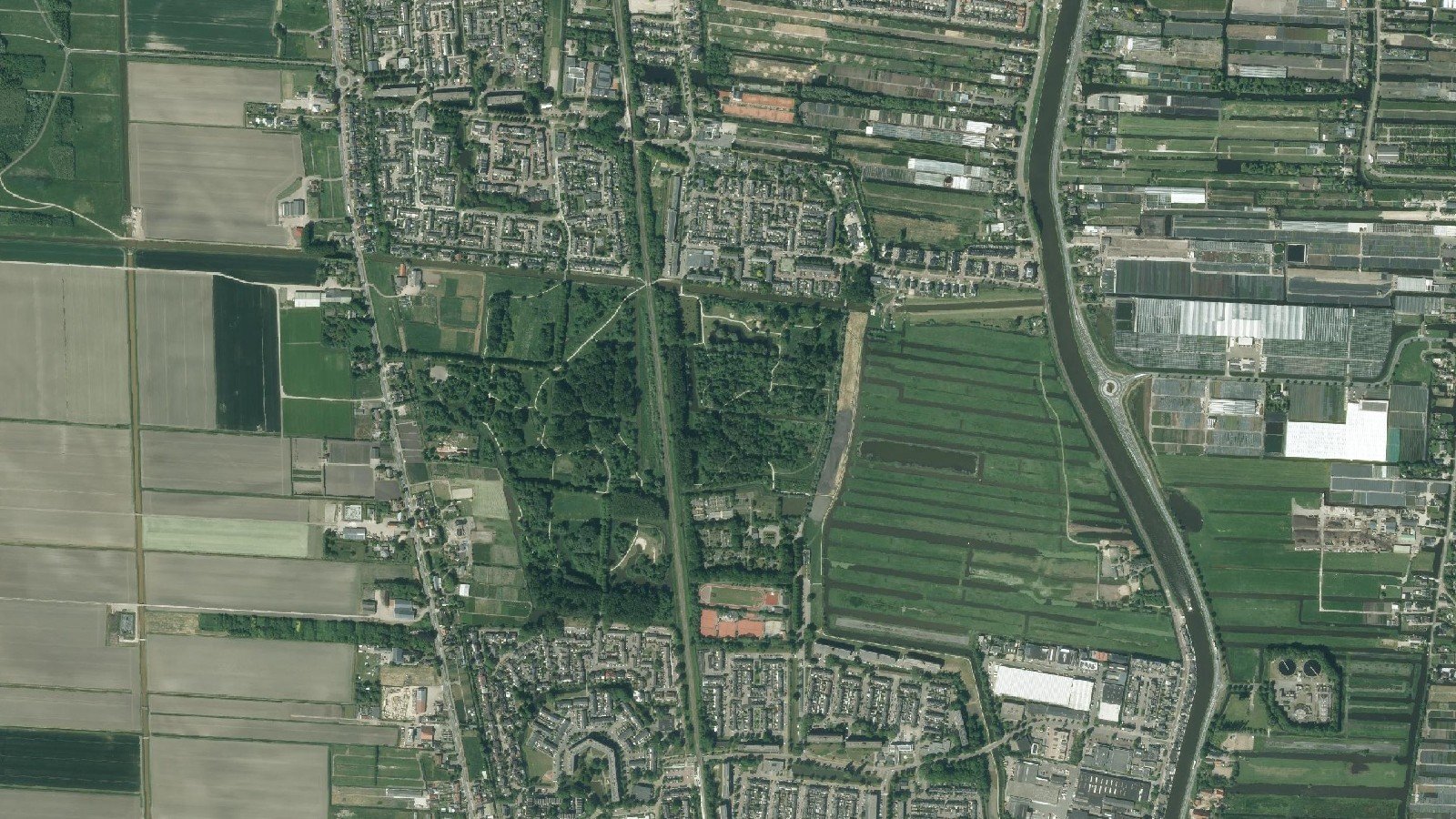 Luchtfoto van het Gouwebos tussen Waddinxveen en Boskoop, met de spoorlijn door het midden en de Voorofsche Polder aan de oostzijde.