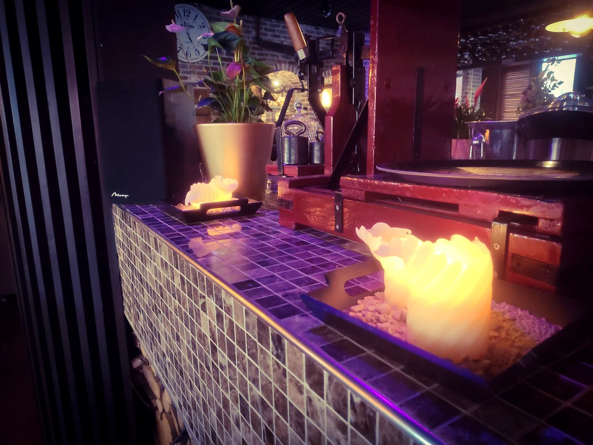 Warm bar- en tafeldetail bij Phoenix Garden met kaarslicht, glaswerk en houten materialen.