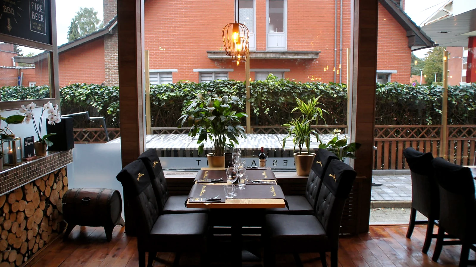 Gedekte tafel aan het raam met planten, hout, leer en daglicht.