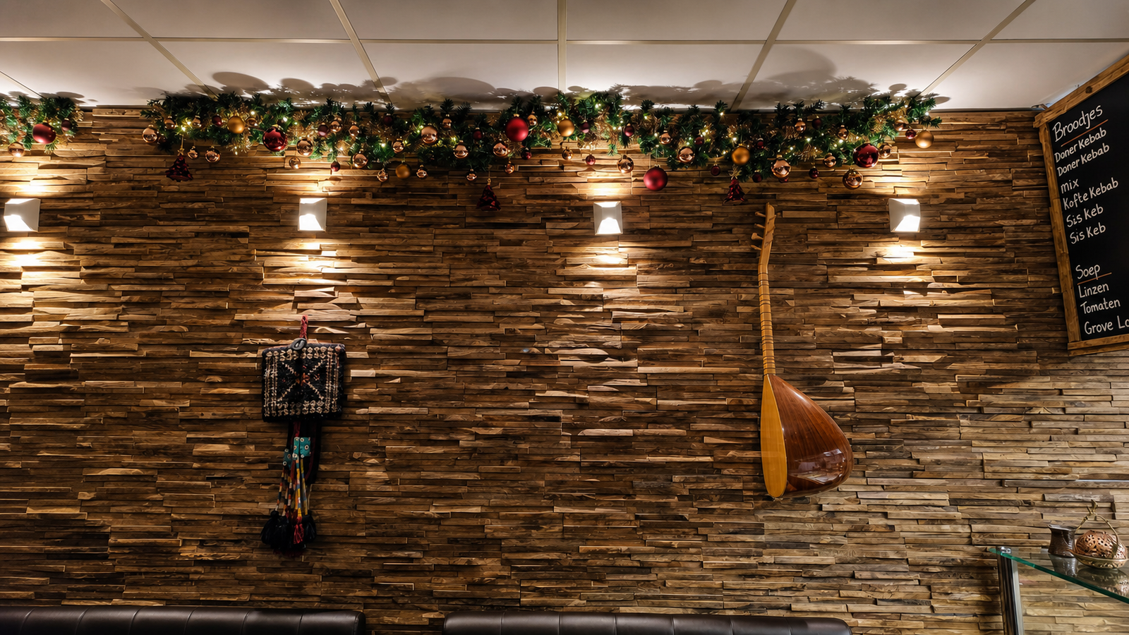 Houten accentwand van Topkapi met warme verlichting en bordeaux-gouden kerstdecoratie.